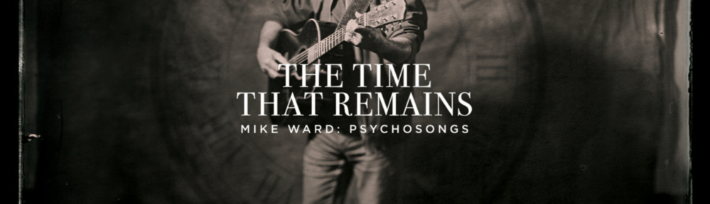 black and white photo of a standing man playing acoustic guitar