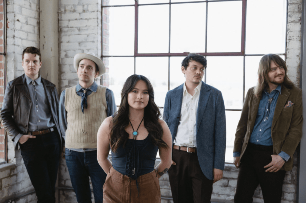 5 people, 4 men and one woman, standing in front of a warehouse style window 