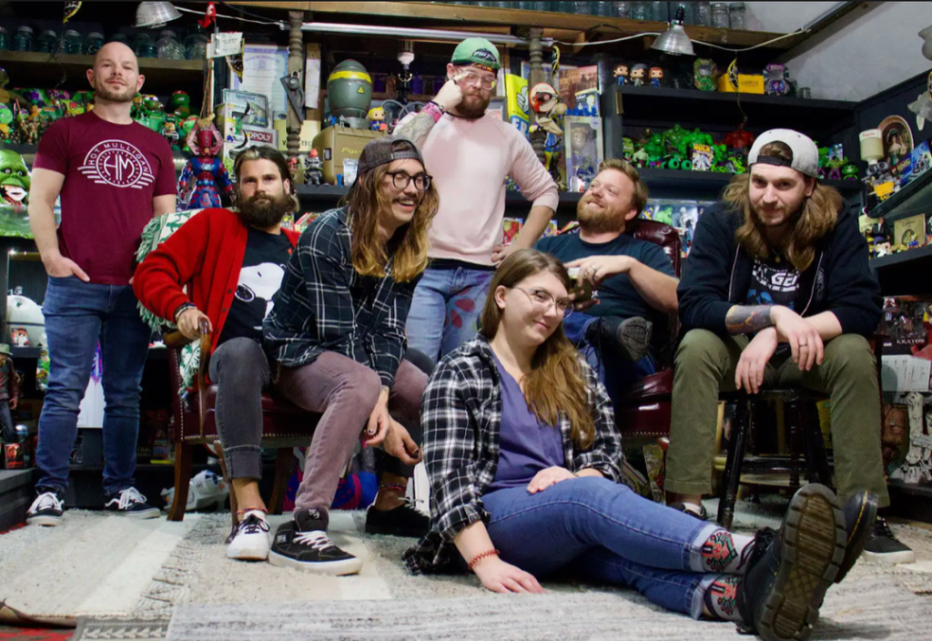 A group of mostly happy looking people, some sitting and some standing.