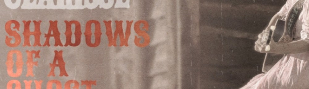 A black and white photo of a woman sitting on a wooden bench. She is wearing a dress and holds a guitar.