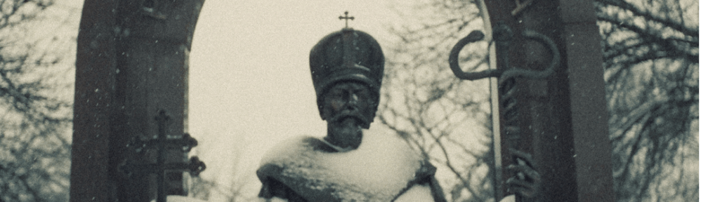 A religious statue of a male figure dressed as a king. He is framed by an inscribed arch.