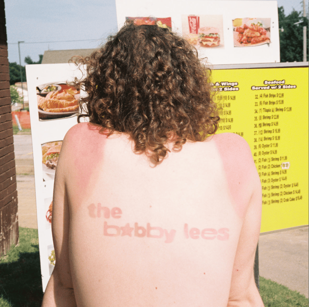 A slightly sunburned person (seen from behind) appears to be looking at a large seafood menu.  The name of this band is also sunburned into their back.  