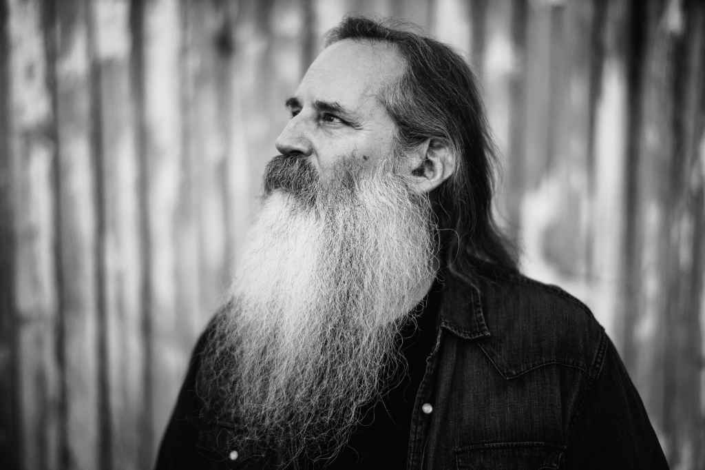 a black and white image of a man with a long beard looking off to the left and upward
