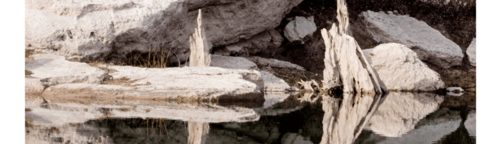 an image of a still body of water in front of a rocky coast