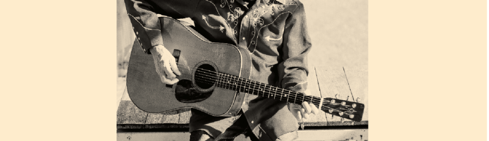 A man sitting on a bench and playing an acoustic guitar.
