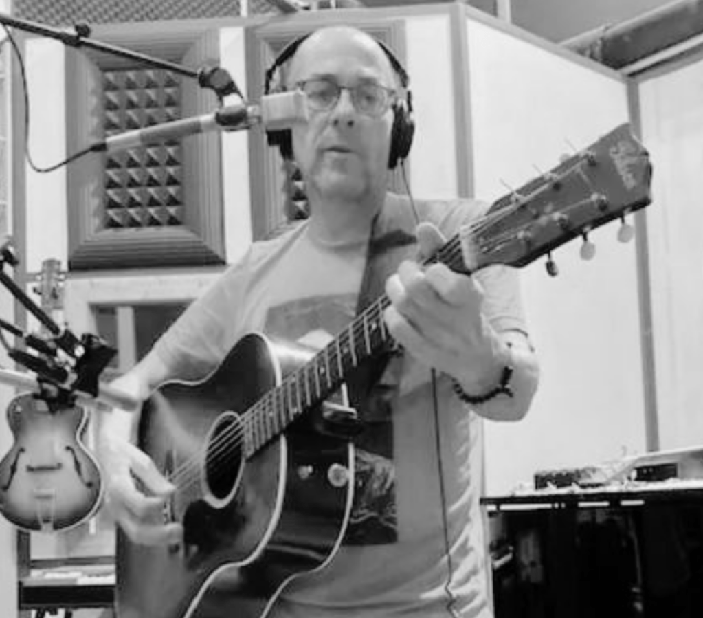 A man in a music studio playing an acoustic guitar